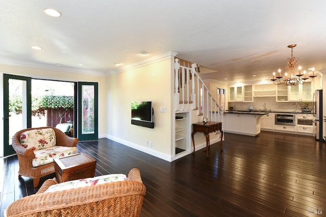 living area with baseboards, dark wood finished floors, ornamental molding, stairs, and a notable chandelier