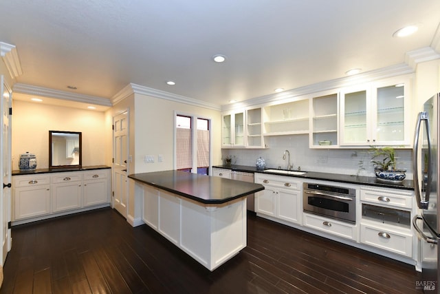 kitchen with appliances with stainless steel finishes, dark countertops, a sink, and a peninsula