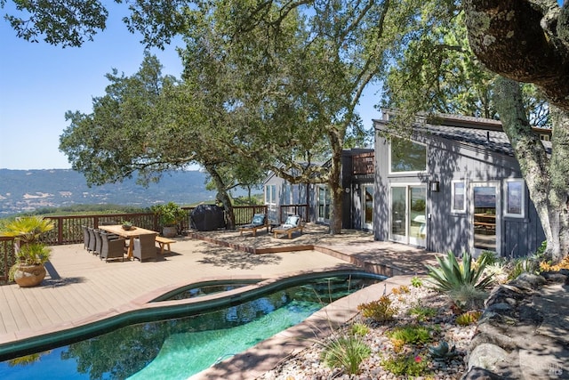 back of house with a wooden deck, fence, a fenced in pool, and an in ground hot tub