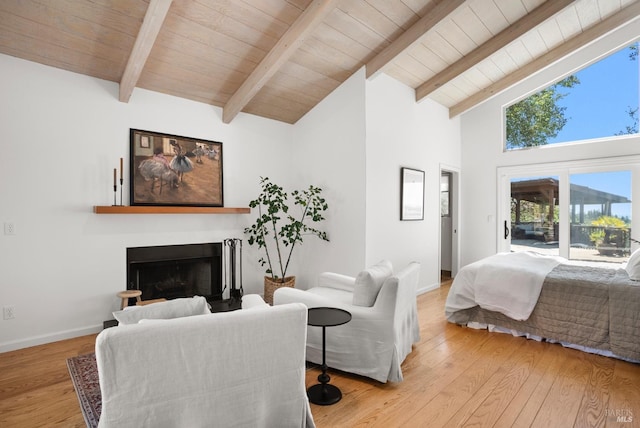 bedroom featuring access to exterior, a fireplace, wood finished floors, and beamed ceiling