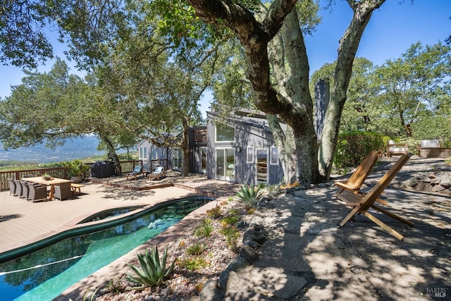 rear view of house with an outdoor fire pit, fence, a deck, and a fenced in pool