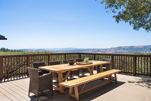 wooden deck with outdoor dining space and a mountain view