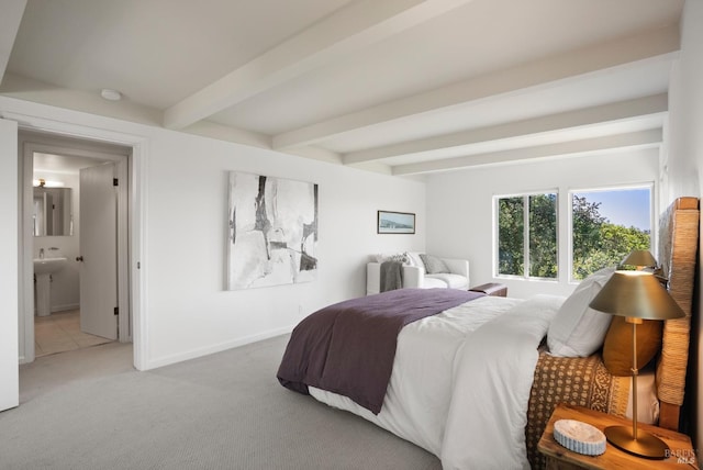 bedroom with carpet floors, baseboards, beam ceiling, and ensuite bathroom