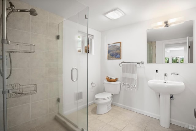 bathroom with baseboards, toilet, tile patterned flooring, a shower stall, and a sink