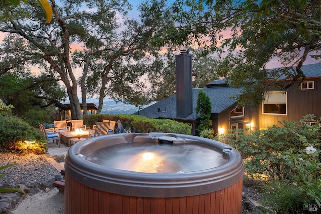 yard at dusk featuring a fire pit, a patio area, and a hot tub