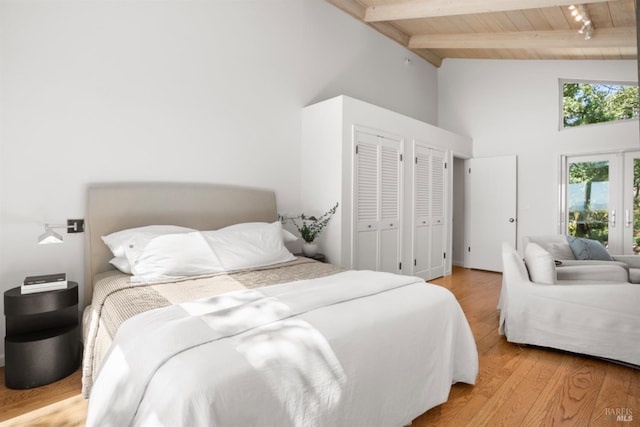 bedroom featuring high vaulted ceiling, wood finished floors, wood ceiling, beam ceiling, and two closets