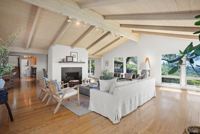 living room featuring wooden ceiling, beamed ceiling, a fireplace, and light wood-style flooring