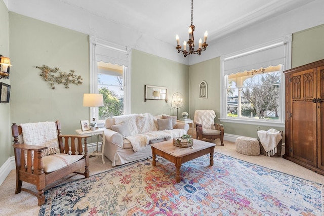 carpeted living area with baseboards and an inviting chandelier