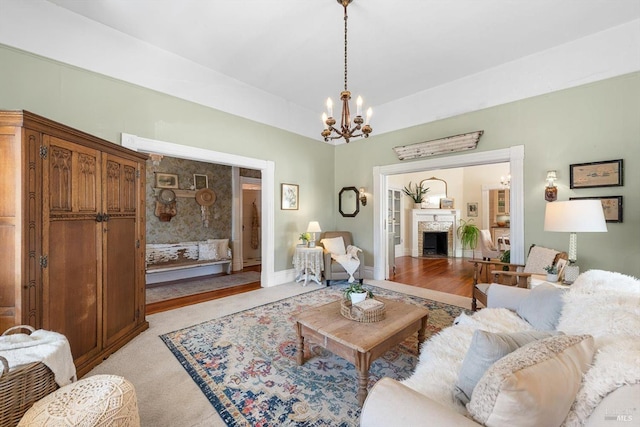 living room featuring baseboards, a fireplace with flush hearth, an inviting chandelier, and light carpet