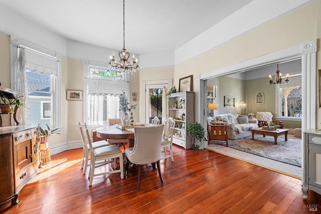 dining area featuring an inviting chandelier, hardwood / wood-style flooring, and baseboards