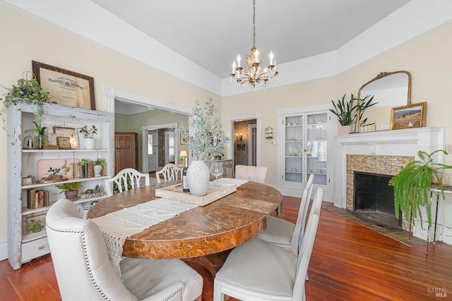 dining space featuring a chandelier, a fireplace with flush hearth, and wood finished floors