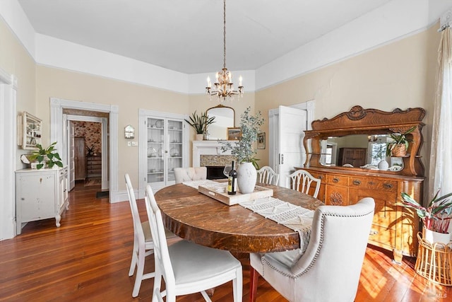 dining space featuring a fireplace, wood finished floors, and a chandelier