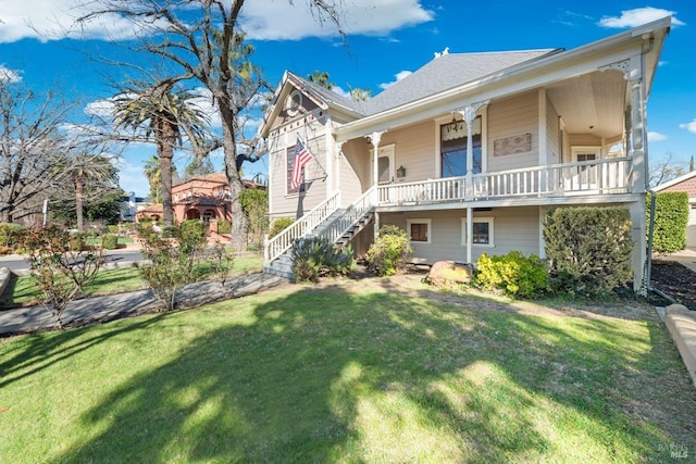 view of front of house with a front yard, stairway, and covered porch