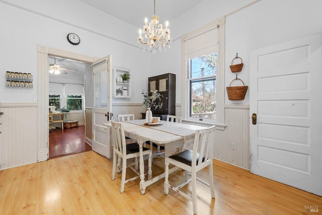 kitchen with light wood finished floors, backsplash, an inviting chandelier, white cabinets, and white appliances