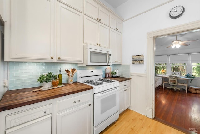 kitchen featuring light wood finished floors, white appliances, tasteful backsplash, and wood counters