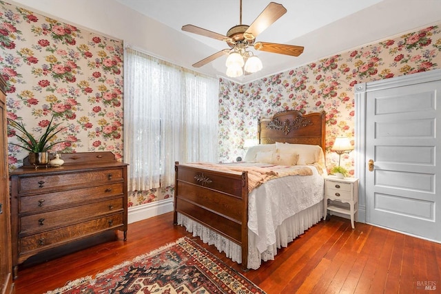 bedroom featuring wallpapered walls, hardwood / wood-style flooring, and baseboards