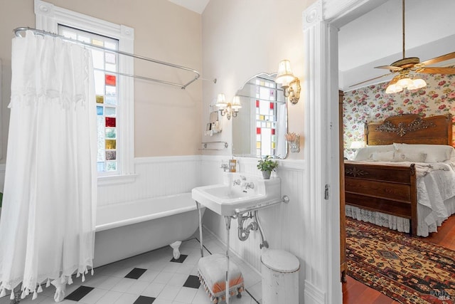 full bath featuring ceiling fan, a tub to relax in, ensuite bath, and wainscoting