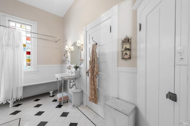 full bath featuring tile patterned floors, a bathtub, and wainscoting