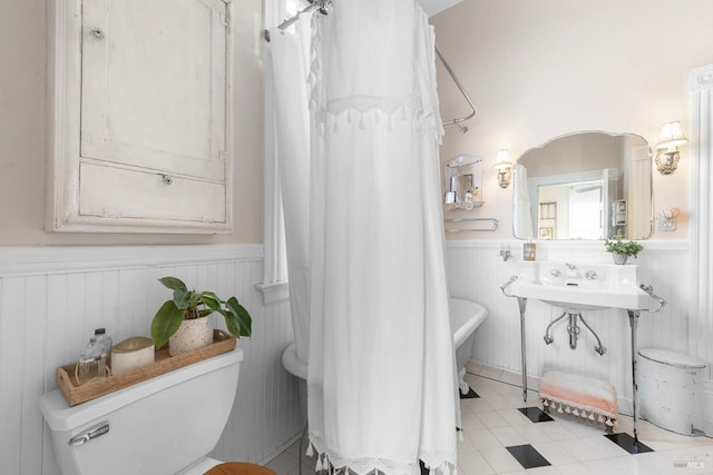 bathroom with curtained shower, toilet, wainscoting, and a washtub