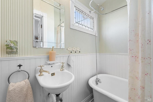 full bath featuring a sink, a freestanding tub, curtained shower, and wainscoting