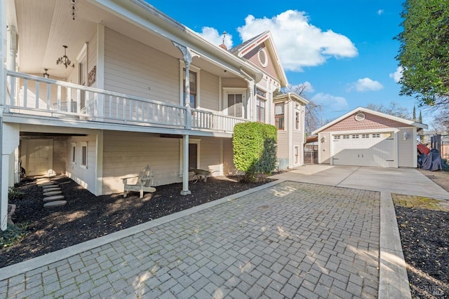 view of side of home with an outdoor structure, a balcony, concrete driveway, and a garage