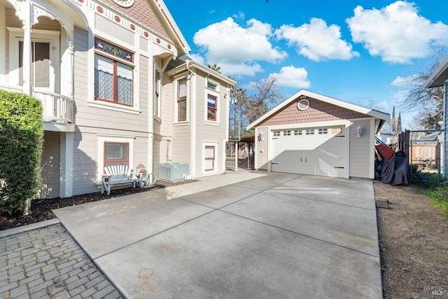 view of side of home with an outbuilding, driveway, central AC, fence, and a garage