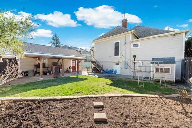 rear view of house with stairs, a patio, a lawn, and a chimney