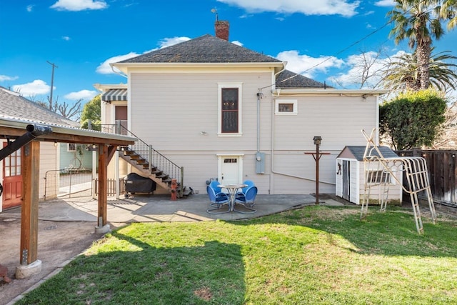 back of house with a lawn, fence, stairway, a chimney, and a patio area