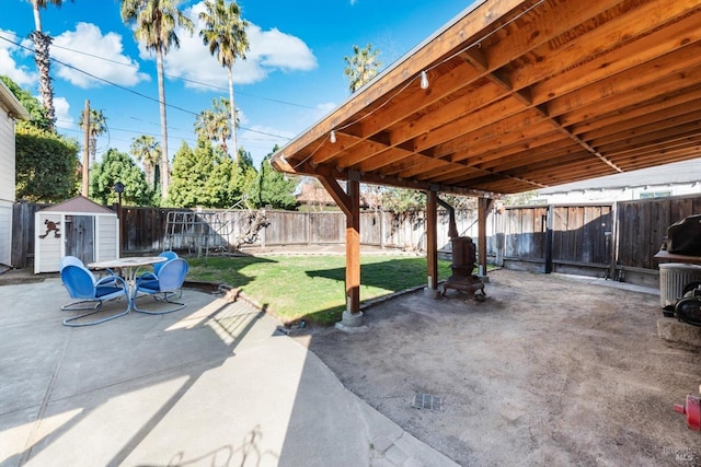 view of patio / terrace with an outbuilding, a storage unit, and a fenced backyard