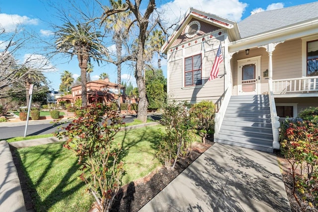 view of front of property with a front lawn, stairway, and covered porch