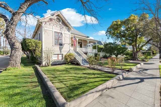 victorian home featuring stairway, covered porch, and a front yard