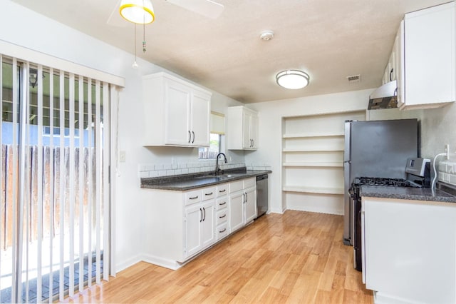 kitchen featuring dark countertops, range with gas stovetop, white cabinets, and stainless steel dishwasher