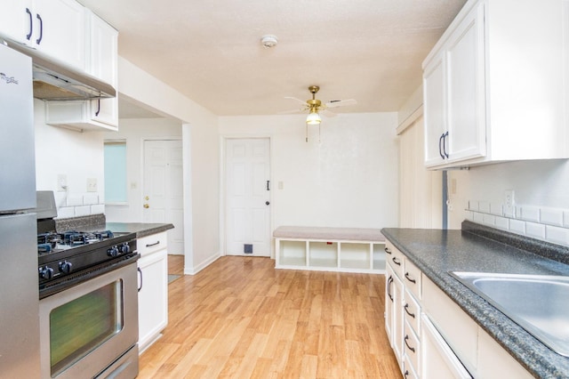 kitchen featuring light wood-style flooring, a sink, dark countertops, white cabinetry, and stainless steel appliances