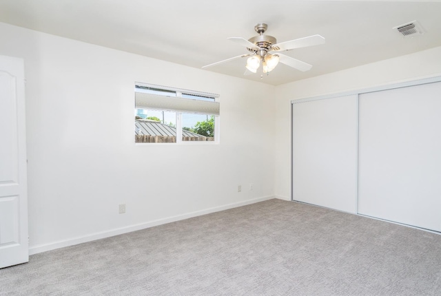 unfurnished bedroom with visible vents, a closet, carpet flooring, baseboards, and ceiling fan