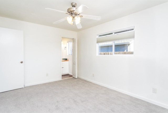 unfurnished bedroom featuring ensuite bath, carpet flooring, a ceiling fan, and baseboards