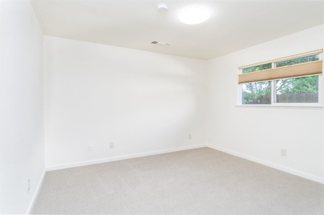 spare room with visible vents, light colored carpet, and baseboards