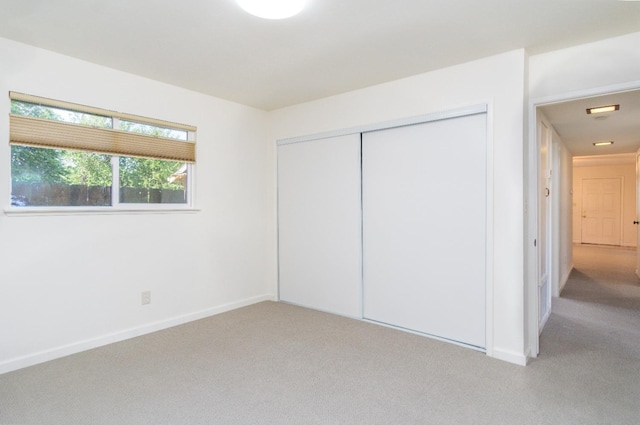 unfurnished bedroom with light carpet, baseboards, and a closet