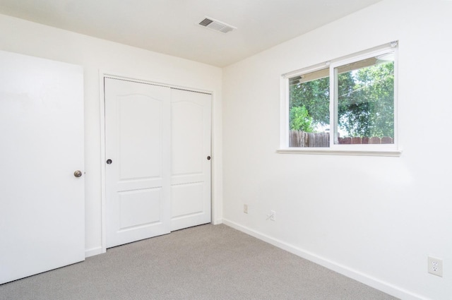 unfurnished bedroom with visible vents, carpet floors, baseboards, and a closet