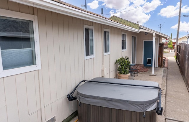 view of patio with a hot tub and fence