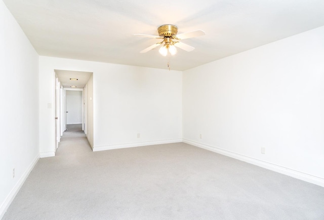 spare room with a ceiling fan, baseboards, and light carpet