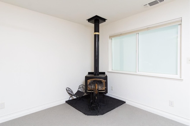 details featuring visible vents, carpet flooring, a wood stove, and baseboards