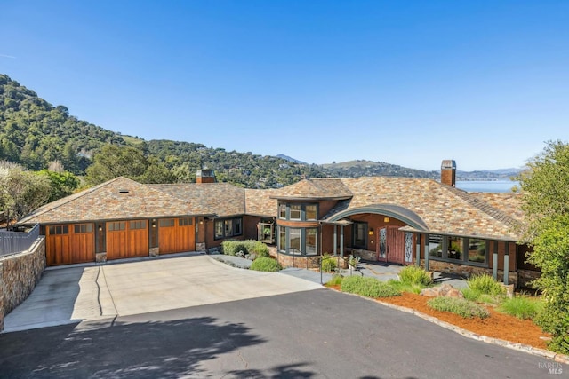 view of front facade featuring a garage, driveway, a chimney, and fence