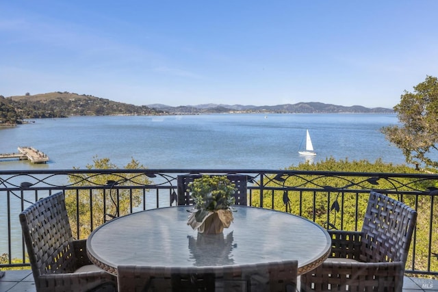 balcony featuring a water and mountain view and outdoor dining space