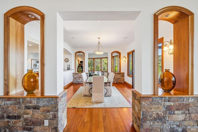 dining room featuring arched walkways, baseboards, and wood finished floors