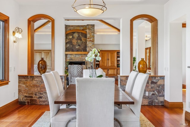 dining area with a fireplace, baseboards, and wood finished floors