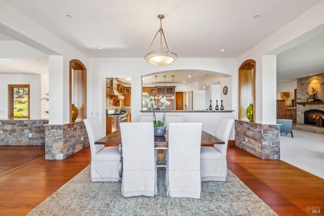 dining area with a large fireplace, wood finished floors, and recessed lighting