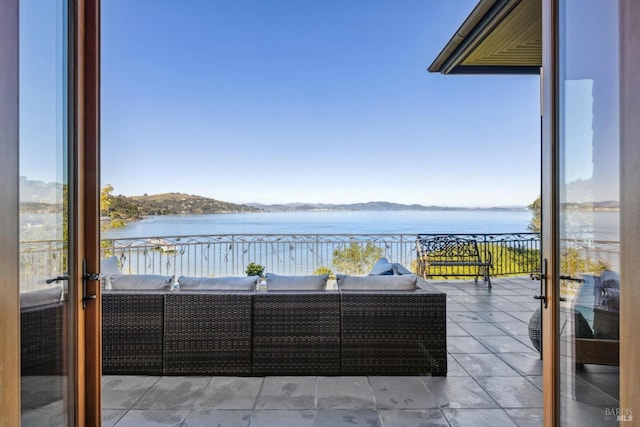 view of patio with a balcony, a water view, and outdoor lounge area