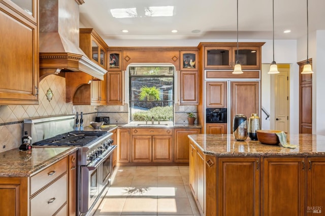 kitchen with premium appliances, brown cabinetry, custom range hood, and light tile patterned floors