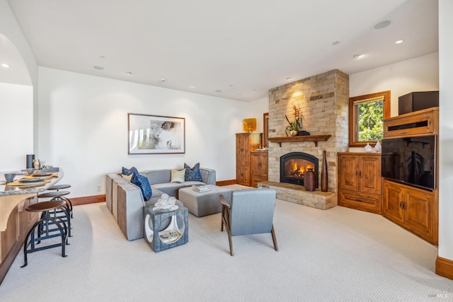 living area featuring light carpet, a stone fireplace, baseboards, and recessed lighting