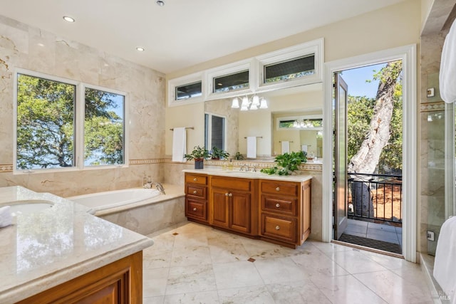 bathroom with a wealth of natural light, vanity, recessed lighting, and a bath